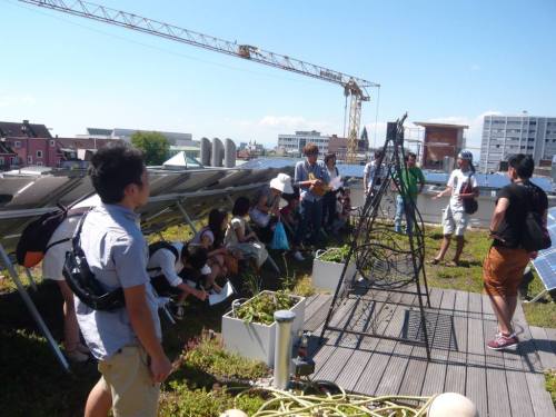 太陽電池の下の日影で多くの参加者は英揮さんのレクチャーを聴く。